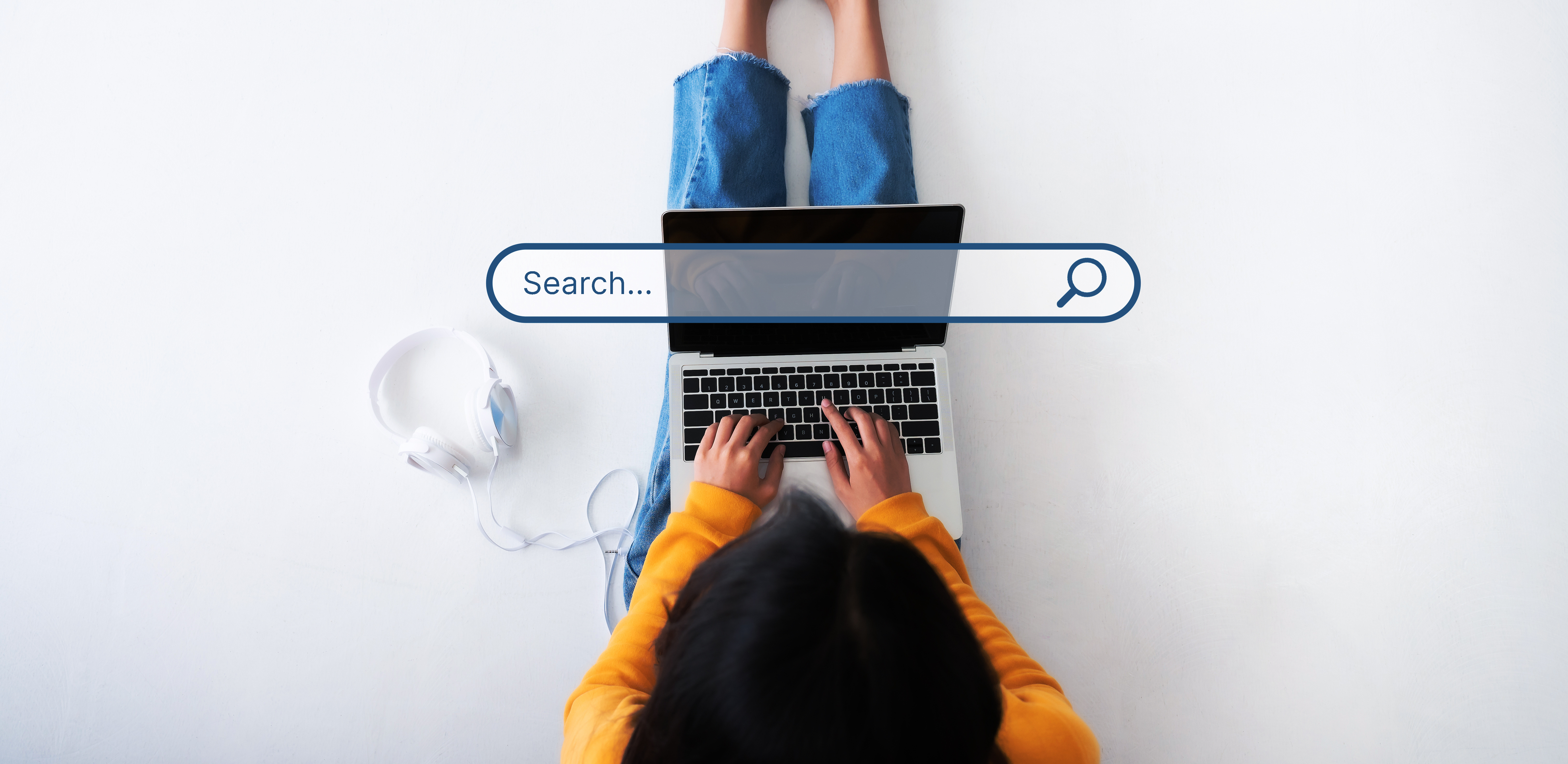 Schüler*in sitzt auf dem Boden mit dem Computer und recherchiert