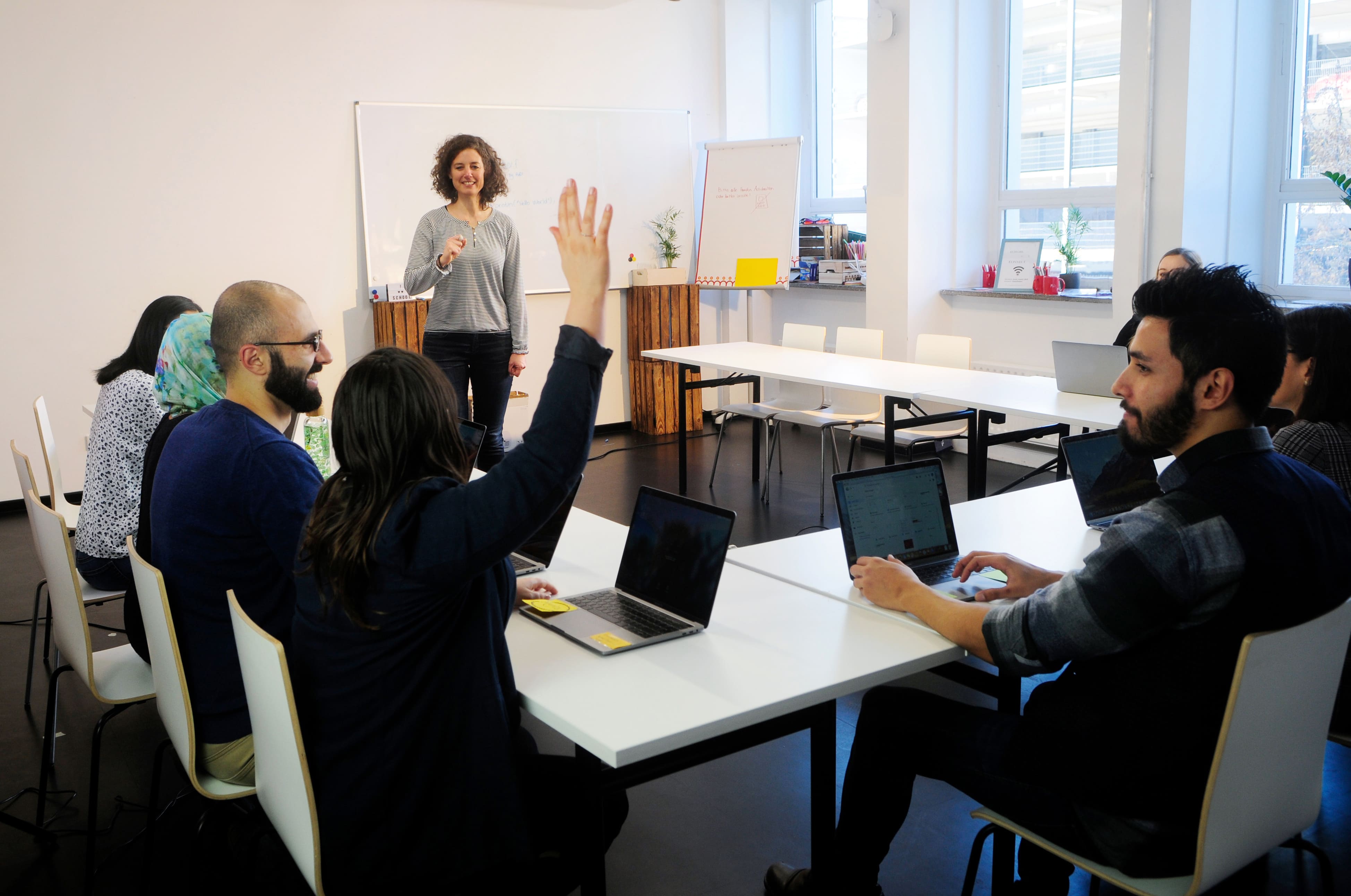 Menschen am Laptop an Tischen sitzend 