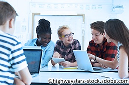 Mehrere Lernende sitzen am Tisch mit Laptops