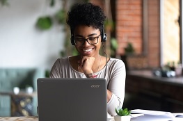 Frau sitzt mit Headset am Laptop