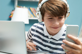 Film ab! Schulportal Jugend und Finanzen ab sofort mit Videoclips und eigenem YouTube-Kanal Junge mit Kopfhörer am Smartphone und Laptop