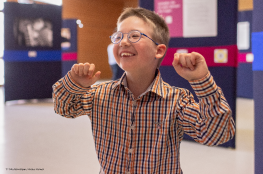 Digital-inklusive Bildung macht alle Kinder stark Kleiner Junge hebt lachend die Arme