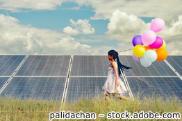 Mädchen mit bunten Ballons vor Photovoltaikanlage