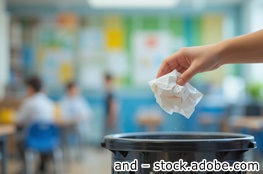 News Online-Workshop: Mülltrennung an Schulen – Wie Entsorger effektiv unterstützen Hand wirft zerknülltes Papier in einen Papierkorb in einem Klassenzimmer
